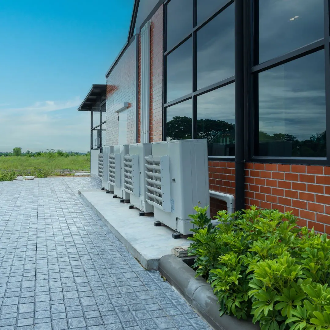 Air conditioning condensers lined up along the wall of a commercial building