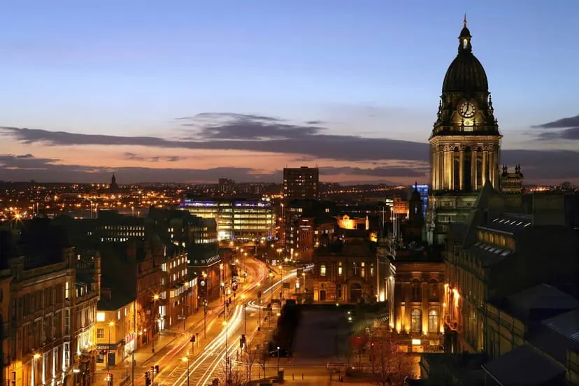 A clock tower and city-centre streets lit up at dusk
